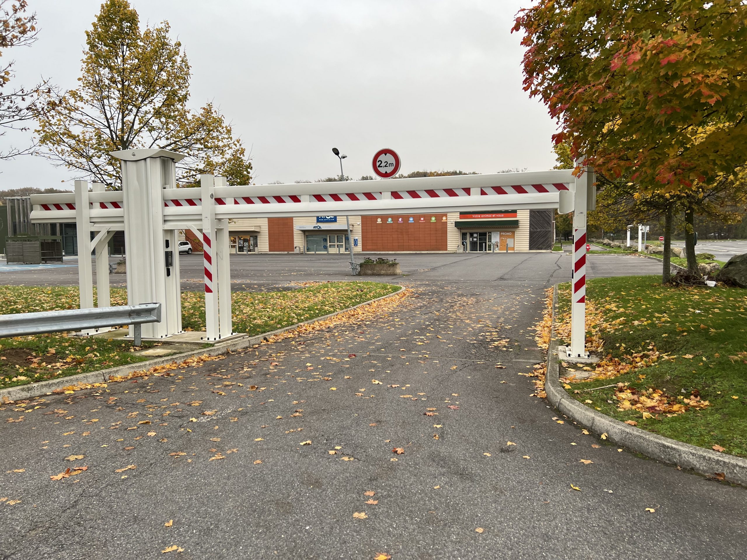 Poutre coulissante motorisée blanche installée à l'entrée d'un parking commercial
