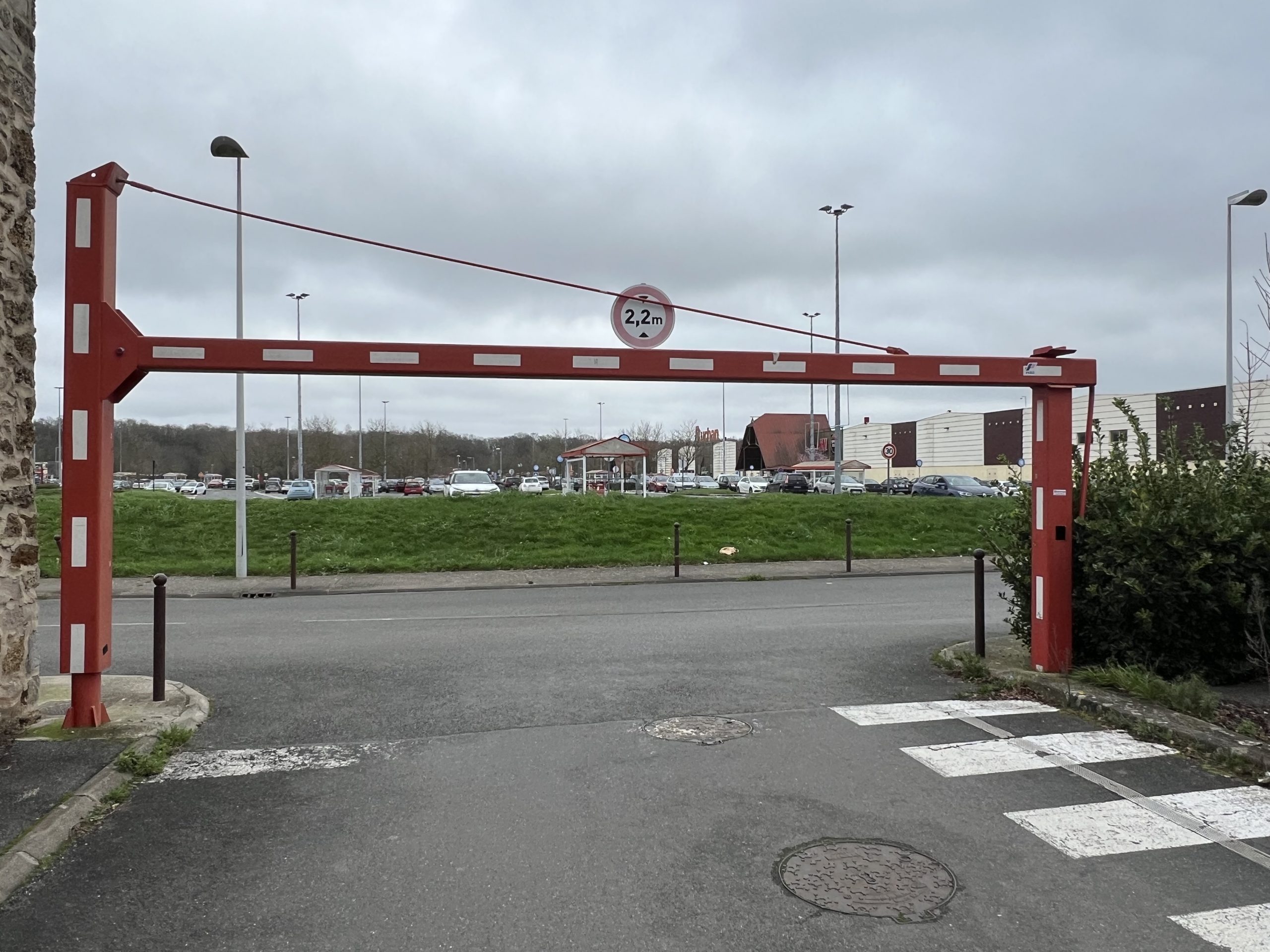 Poutre pivotante manuelle rouge et blanche installée par JCD Services sur un parking