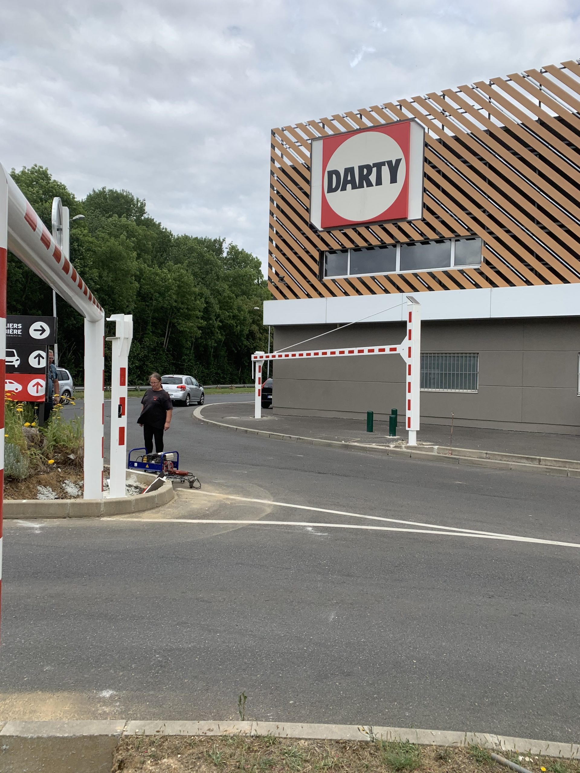 Poutre pivotante manuelle blanche et rouge à l'entrée d'un magasin Darty