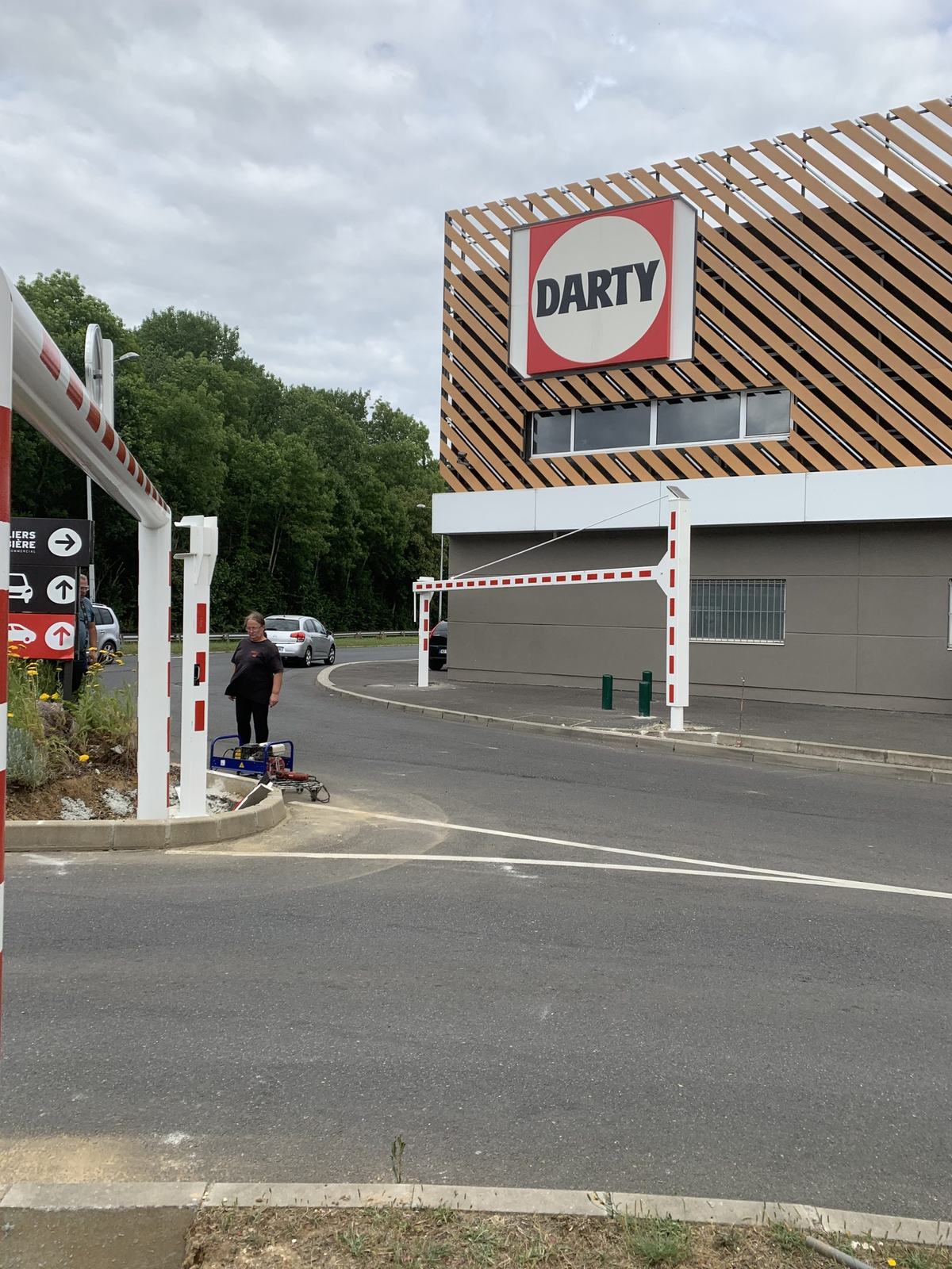 Poutre pivotante manuelle blanche et rouge à l'entrée d'un magasin Darty