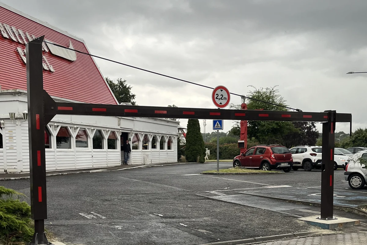 Poutre manuelle de limitation de hauteur à 2,20 m fermant l'accès au parking d'un restaurant, JCD Services