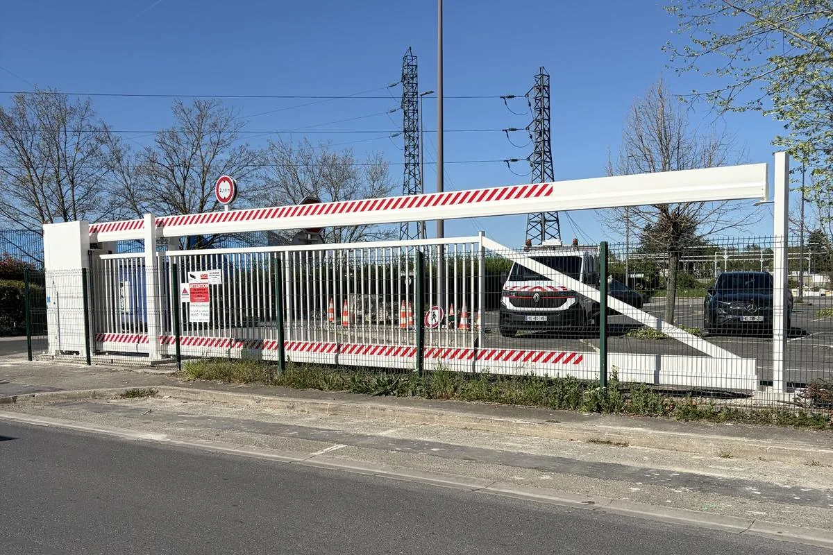 Poutre coulissante motorisée blanche fermant l'accès d'un parking d'entreprise en Île-de-France, installée par JCD Services