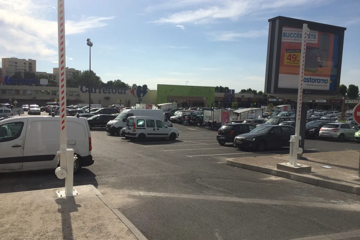 Barrière levante manuelle filtrant l'accès d'un parking de zone commerciale, JCD Services