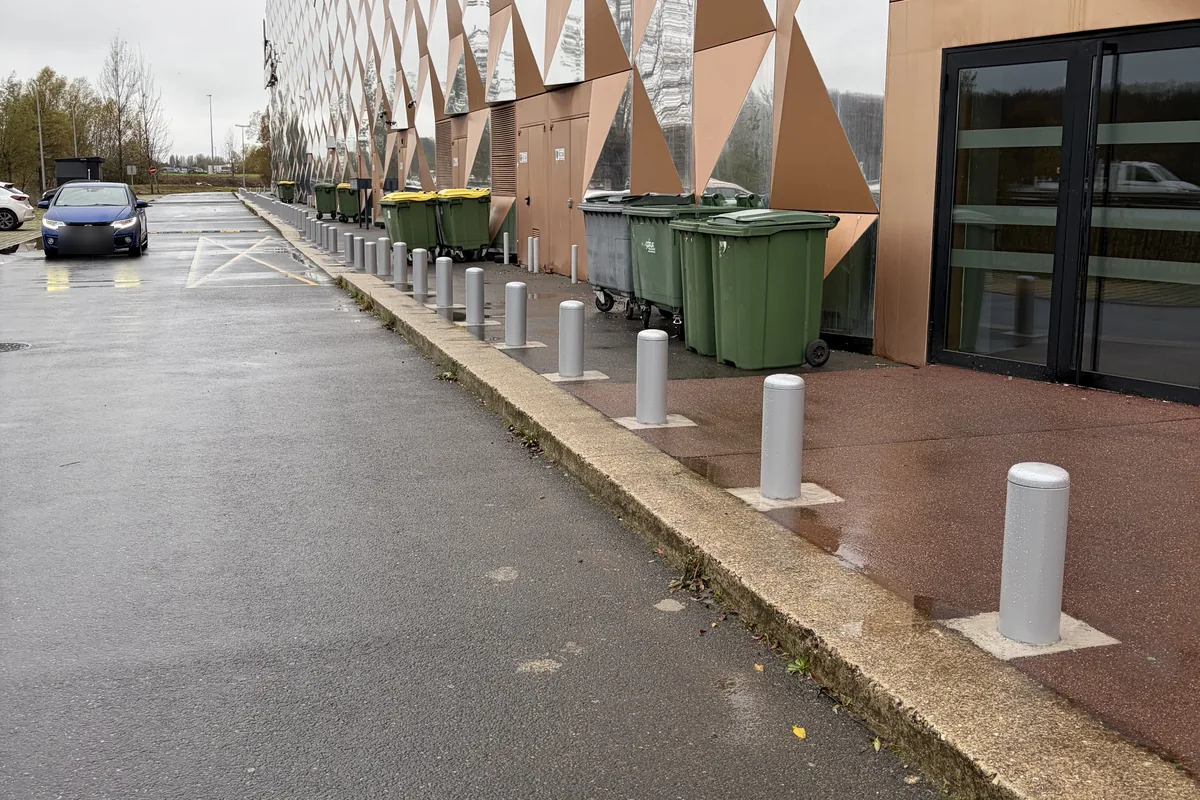 Bornes fixes acier délimitant une allée de livraison le long d'un bâtiment, JCD Services