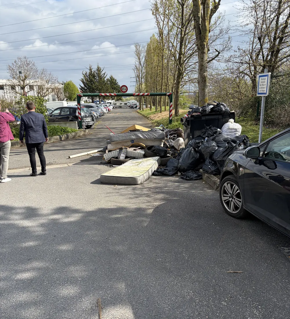 Dépôt sauvage de pneus, matelas et sacs poubelle sous un portique de 2 m dans une zone d'activité à Osny (95)